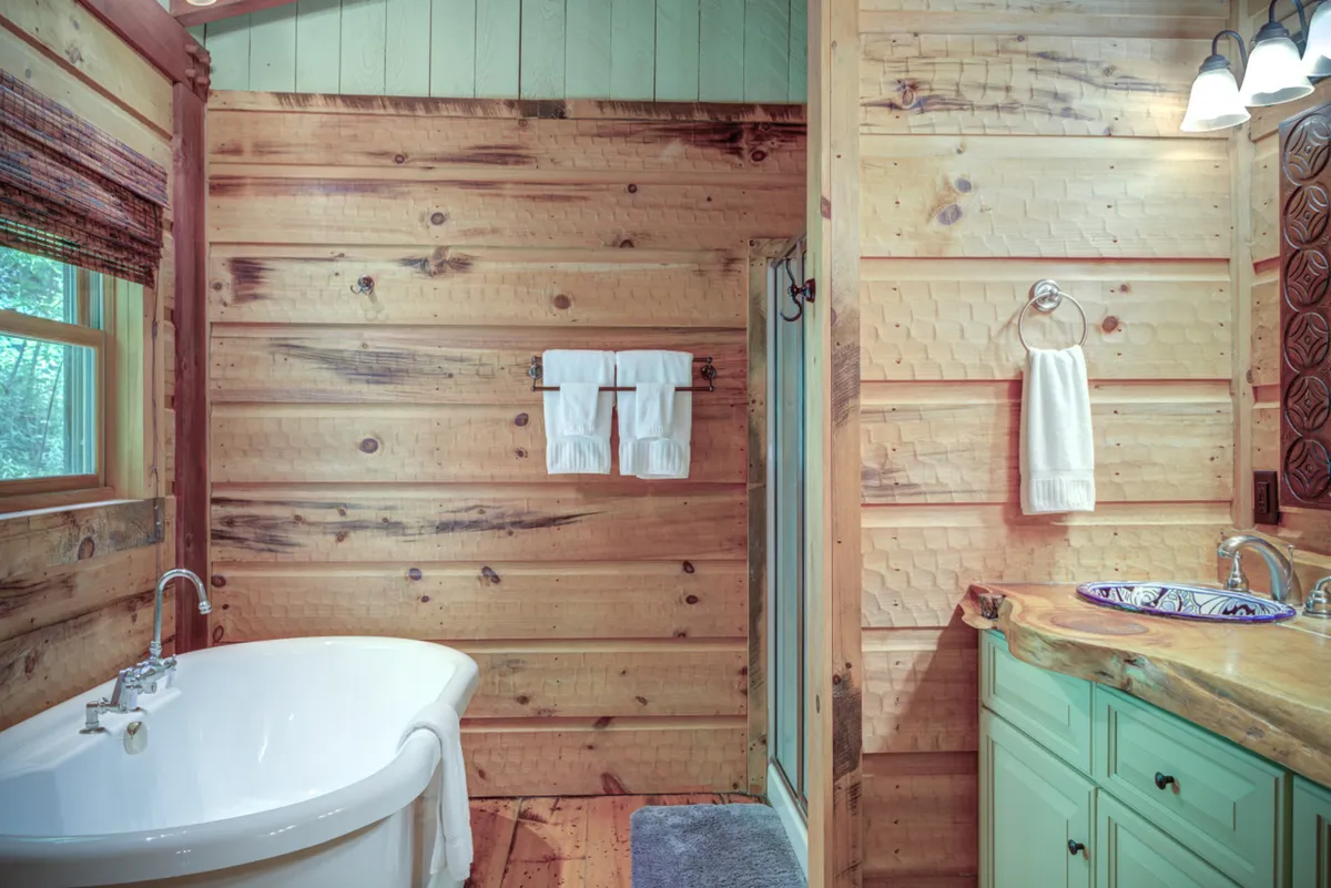 A spa-inspired bathroom with a freestanding soaking tub, wooden vanity, shower stall, and warm natural wood walls. Natural light streams in, creating a tranquil, luxurious environment ideal for self-care and deep relaxation.