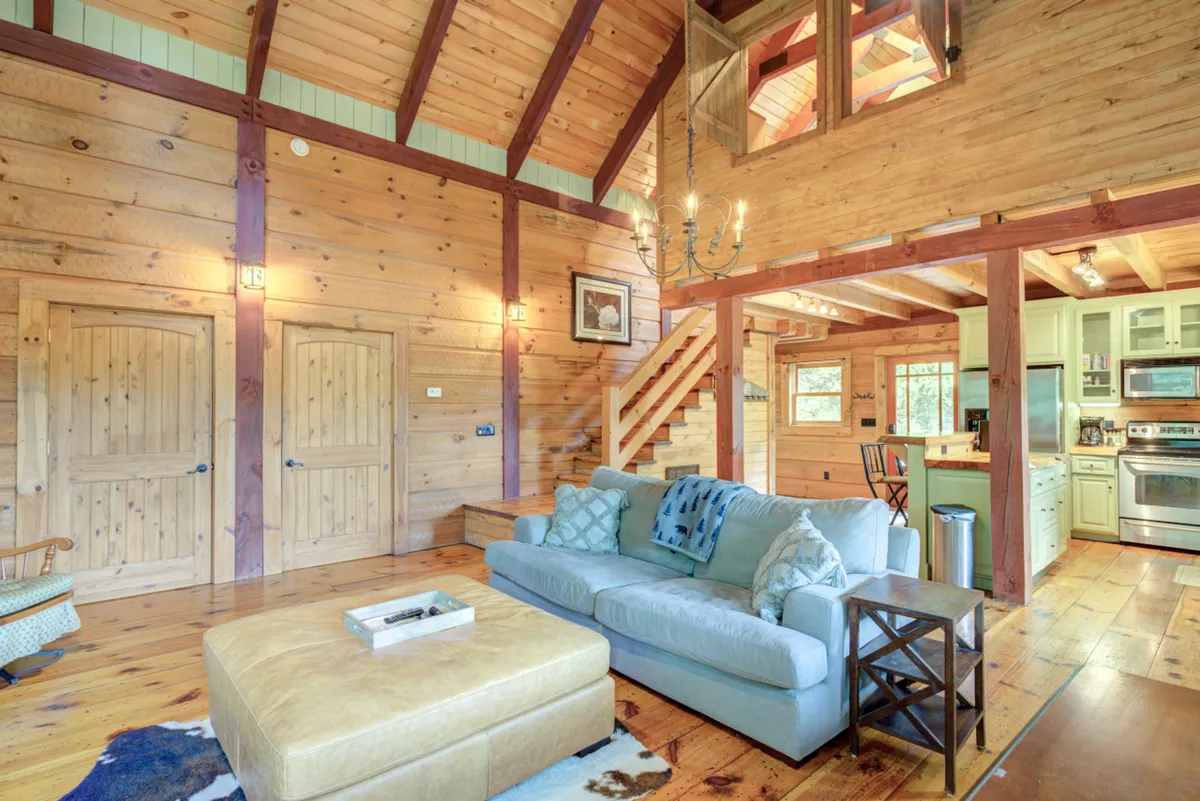 This interior shot highlights a cozy living area with a comfortable sofa, a chandelier, a staircase, and an open view of the kitchen. The warm ambiance and spacious layout suggest a perfect spot for family game nights, movie sessions, or unwinding together after a day out, as referenced in the section content.