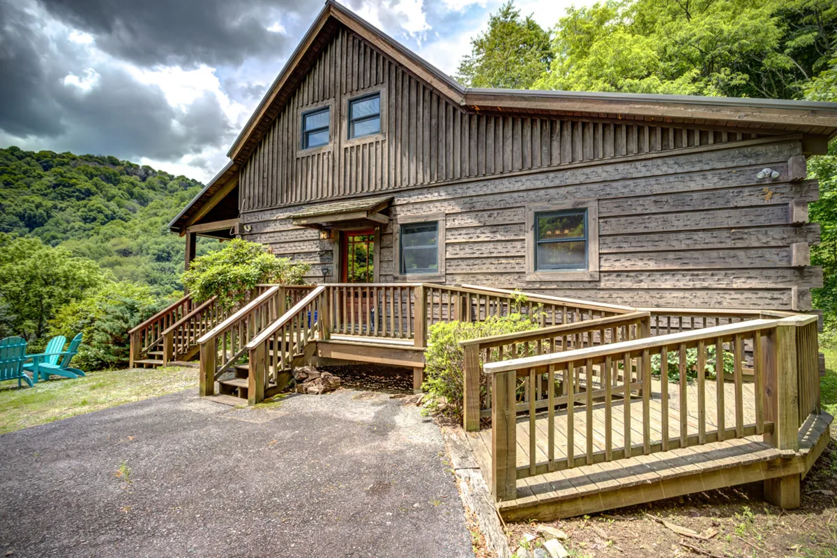 A wooden exterior with a gently sloping ramp leading to the entrance, surrounded by greenery. The ramp and level entry are clearly visible, ensuring accessibility for everyone, including pets and those with mobility considerations.